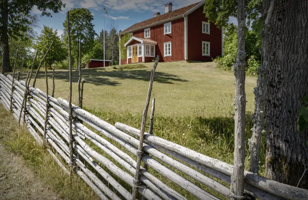 Faluröd stuga och gärdsgård.