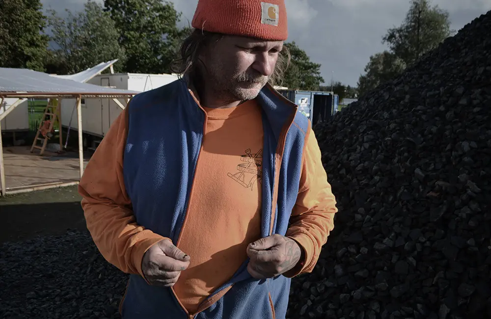 Man i orange tröja och blå väst.