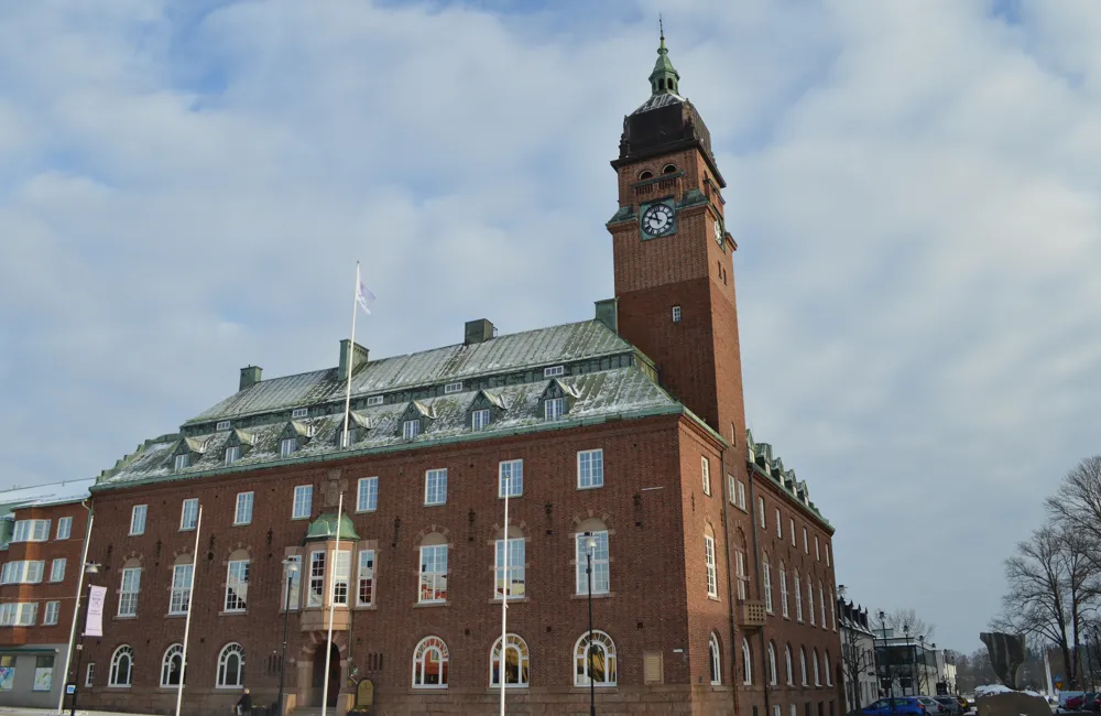 Stor tegelbyggnad med klocktorn mot en blå himmel.
