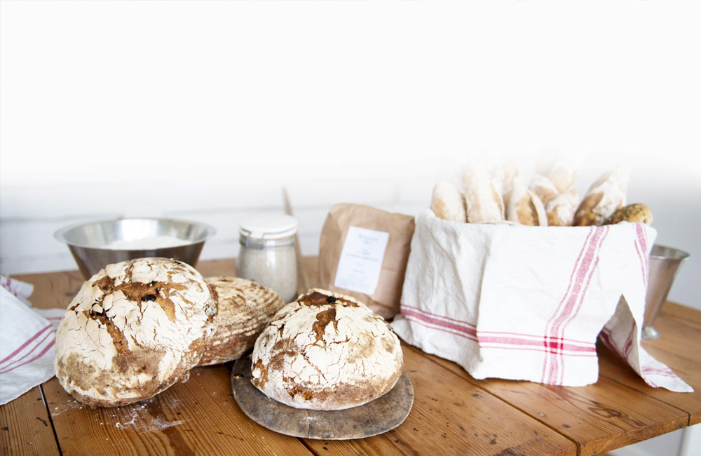 Ett träbord med hembakat bröd och en kökshandduk. 