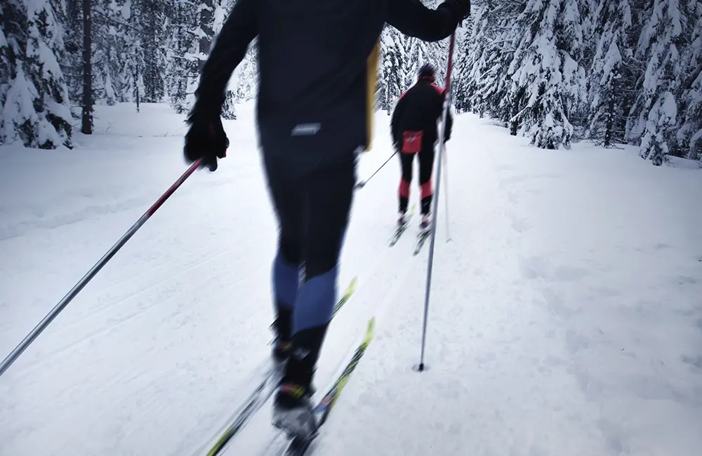 Två personer som åker skidor på snön. 