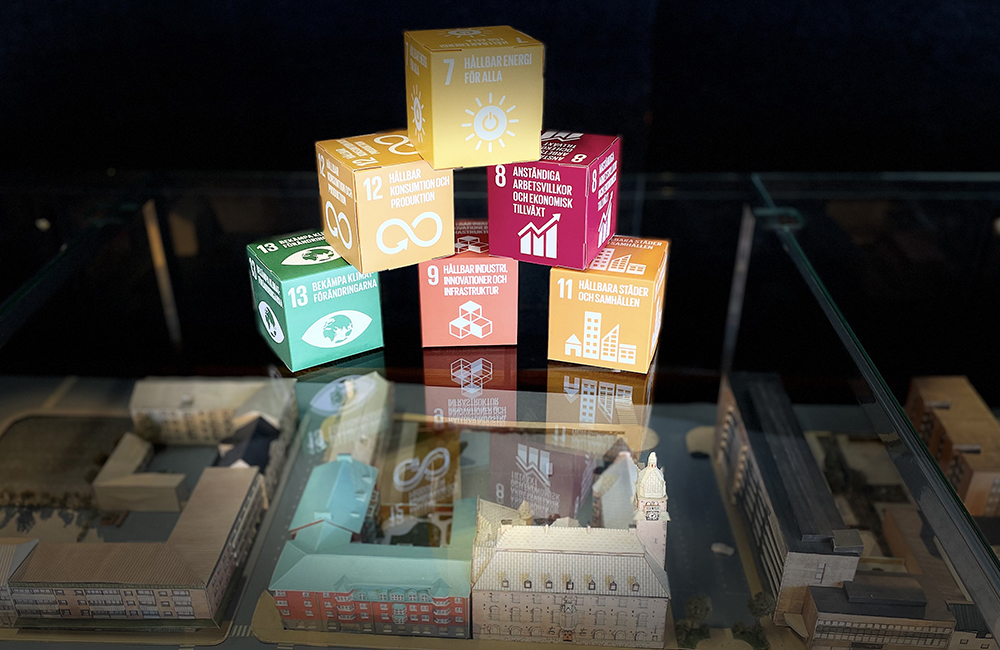 Kartongkuber med text om de olika globala mål som Nässjö kommuns energi- och klimatrådgivare berörs av som står uppe på en glasskiva och är flashade med belysning