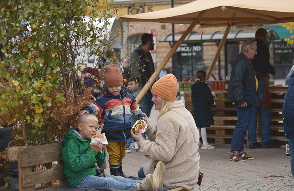 En kvinna och två barn sitter och äter hamburgare på Nässjö Outdoor Festival.