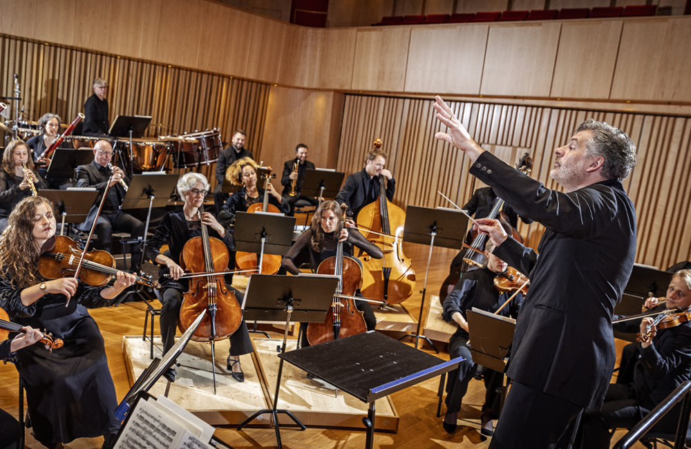 Flera personer i en orkester spelar på olika instrument.