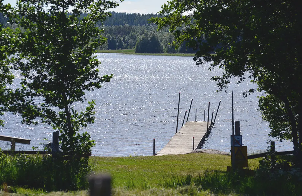 En lummig badplats med brygga och gräsplan