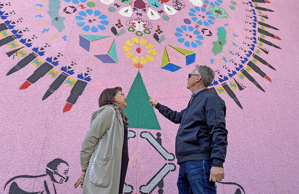 Två personer samtalar framför en väggmålning i Nässjö av Sadia Hussein