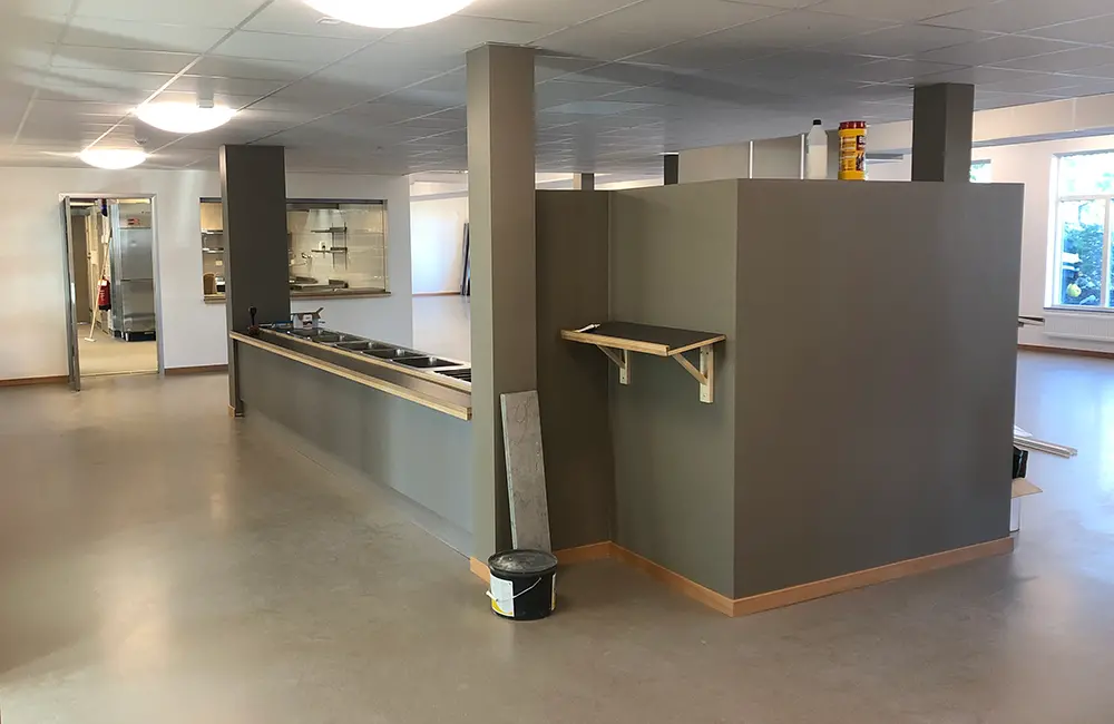 Inomhusmiljö med bespisning, plastgolv och fönster.