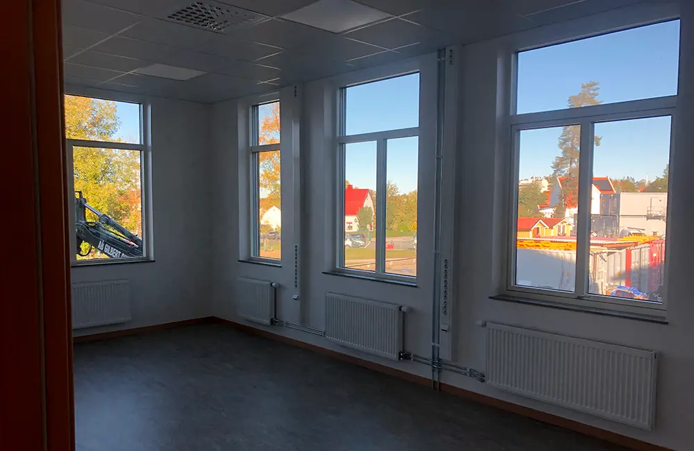 Inomhusmiljö med mörkt golv och fönster.