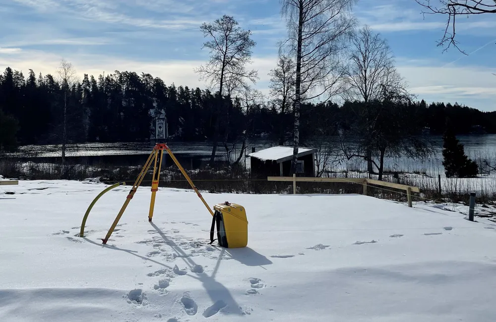 En mätapparat för utstakning står i snö med fotspår i snön runtomkring.