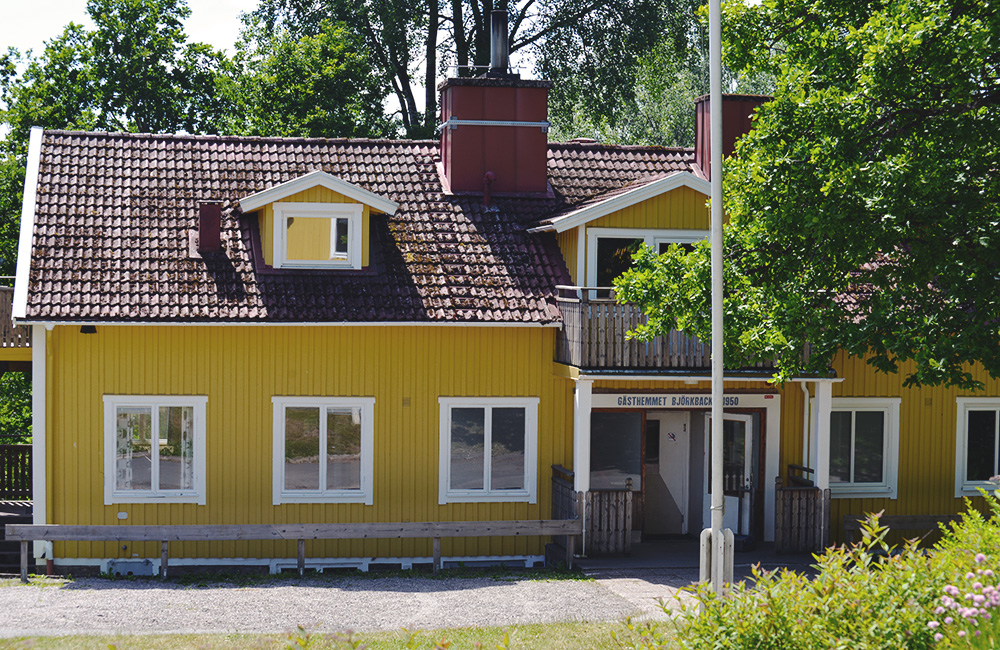 Stort gult hus i lummig trädgård
