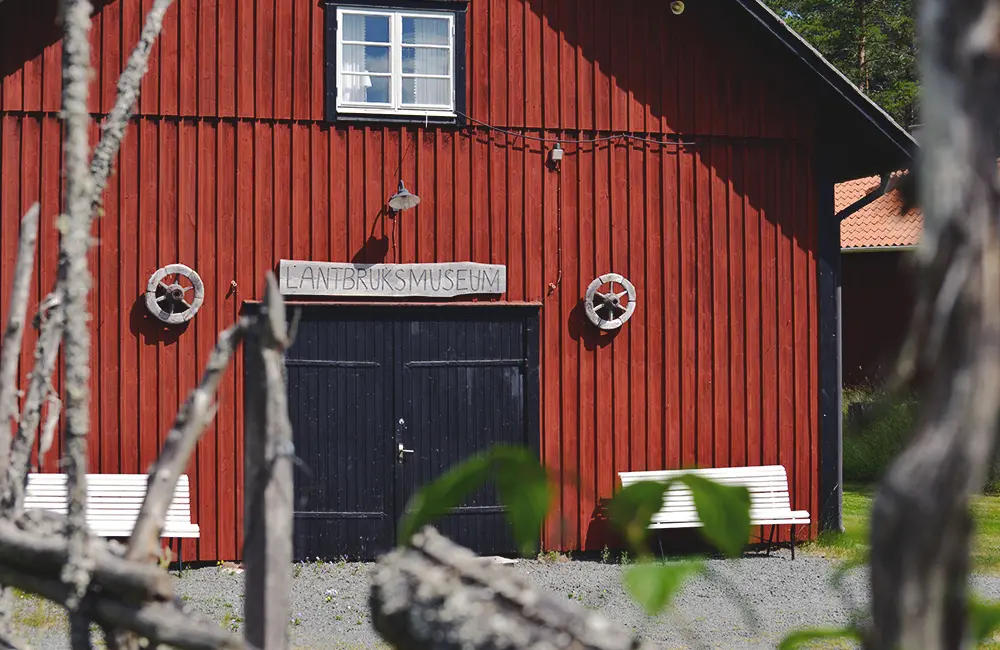 En röd lada med skylten "Lantbruksmuseum" på fasaden.