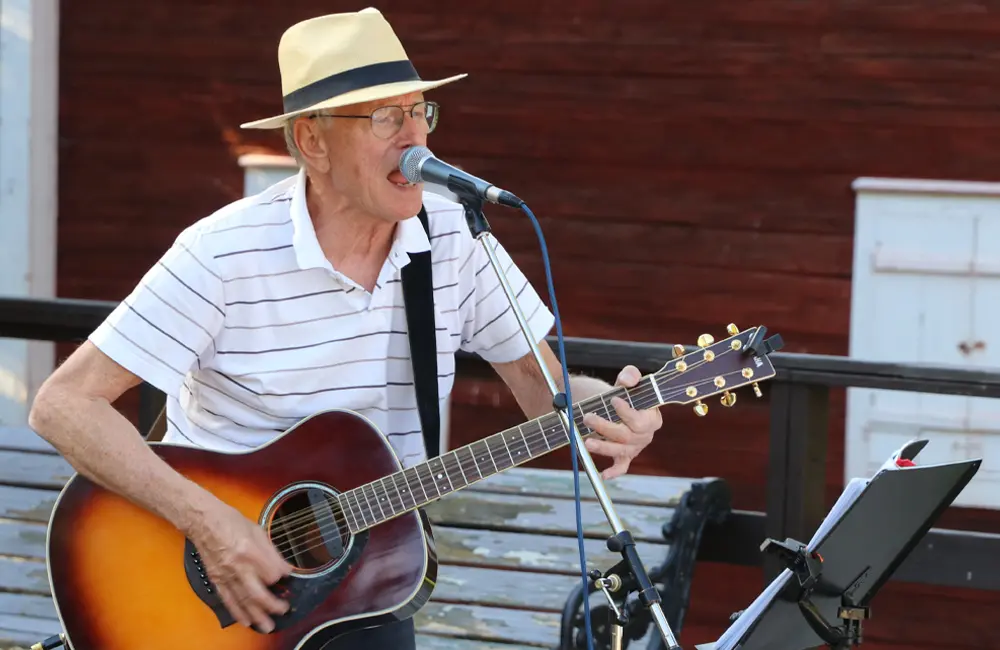 En man i vit hatt spelar på en gitarr.