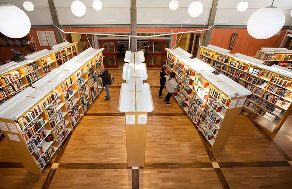 Bil från Brinellgymnasiets bibliotek med höga bokhyllor.