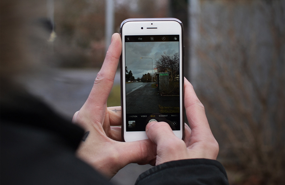 Milton håller i telefonen och tar en bild.