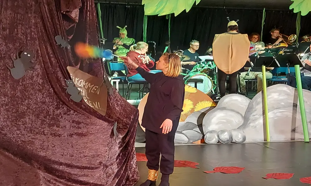 Till vänster i bild står en av de skådespelande myrorna och dammar deras myrstack. I bakgrunden syns stenar och orkestern.