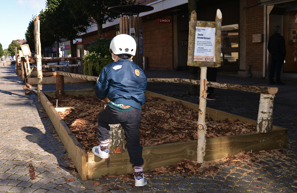 Barn med cykelhjälm på huvudet klättrar i en hinderbana.
