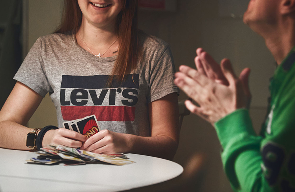Två personer sitter vid ett bord och spelar kortspelet Uno.