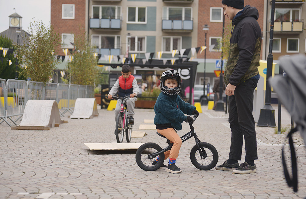Pojke med crosshjälm sitter på en liten mountainbike. I bakgrunden syns enklare cykelhinder och gupp.