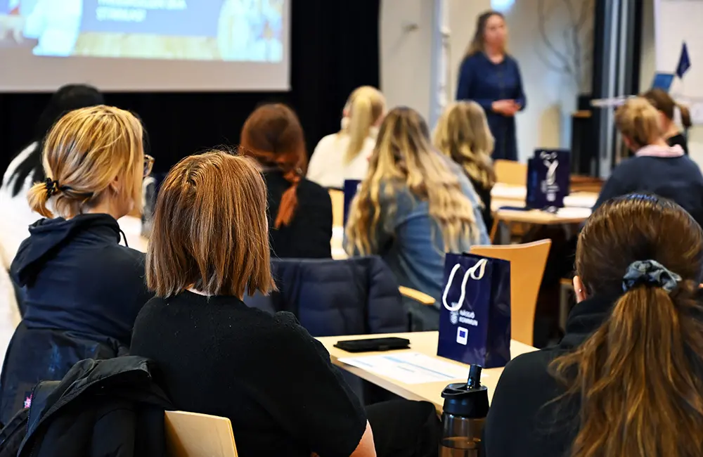 Deltagare lyssnar på föreläsare i en konferenssal.