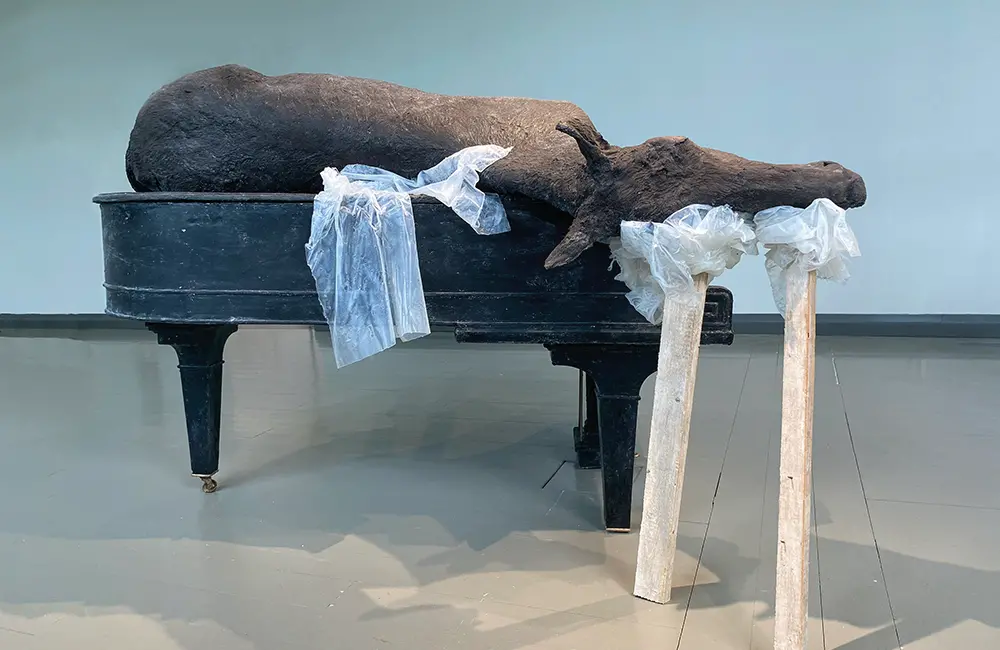 En realistisk skulptur av en häst som ligger på en flygel.