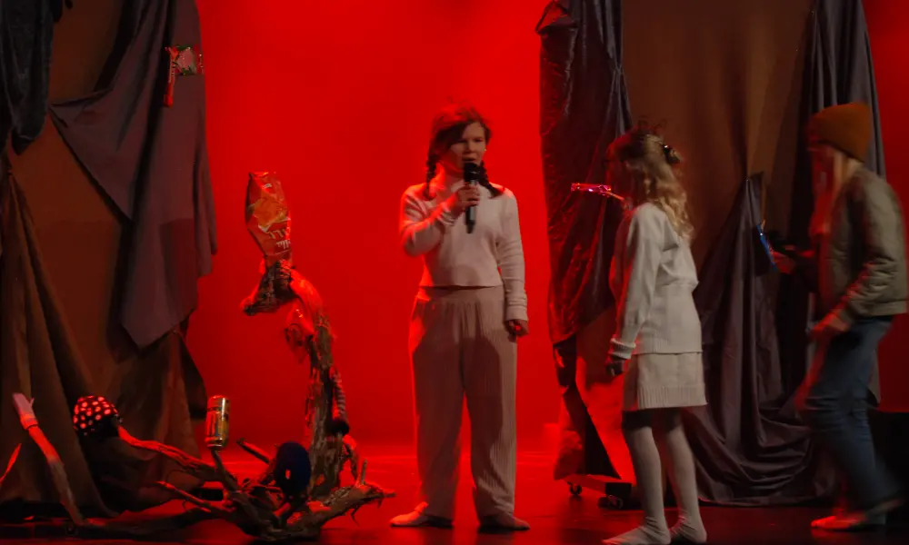 Ljuset på scenen är rött och mystiskt. Några barn agerar på scenen.