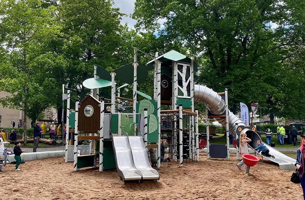 Barn leker i en stor klätterställning med flera torn och rutschkanor på lekplatsen i Stadsparken.
