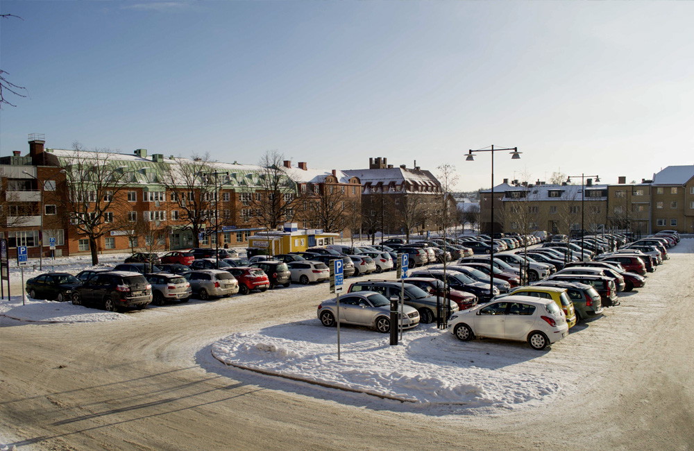 Snöig parkering med bilar i stad.