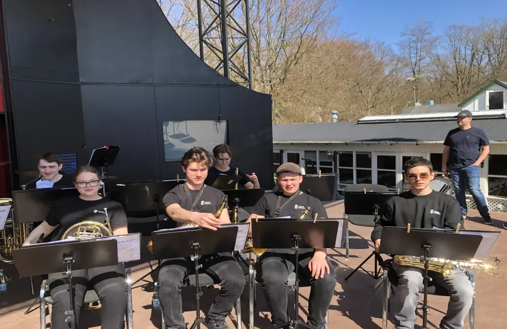 En orkester bestående av ungdomar sitter på en scen, redo att snart börja spela.