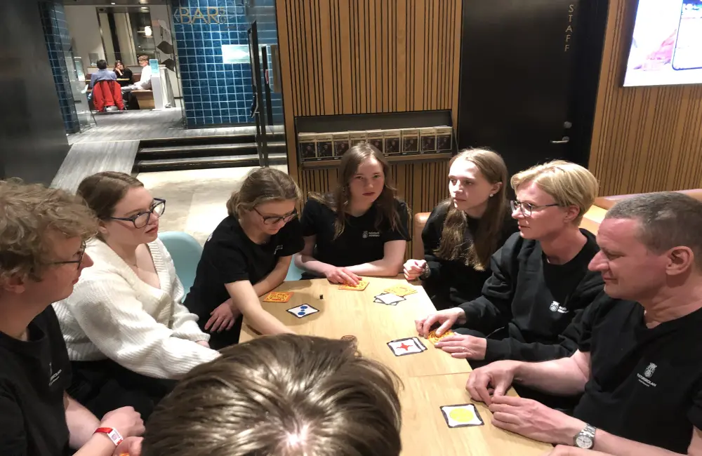 En grupp ungdomar och deras lärare sitter och spelar spel tillsammans.