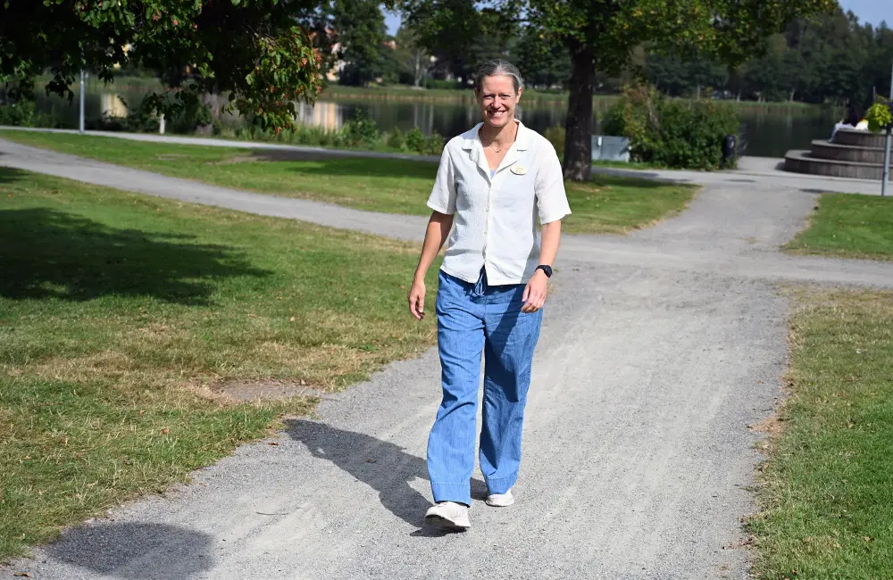Hanna Lundqvist går mot kameran på en grusstig i en park med en sjö i bakgrunden.