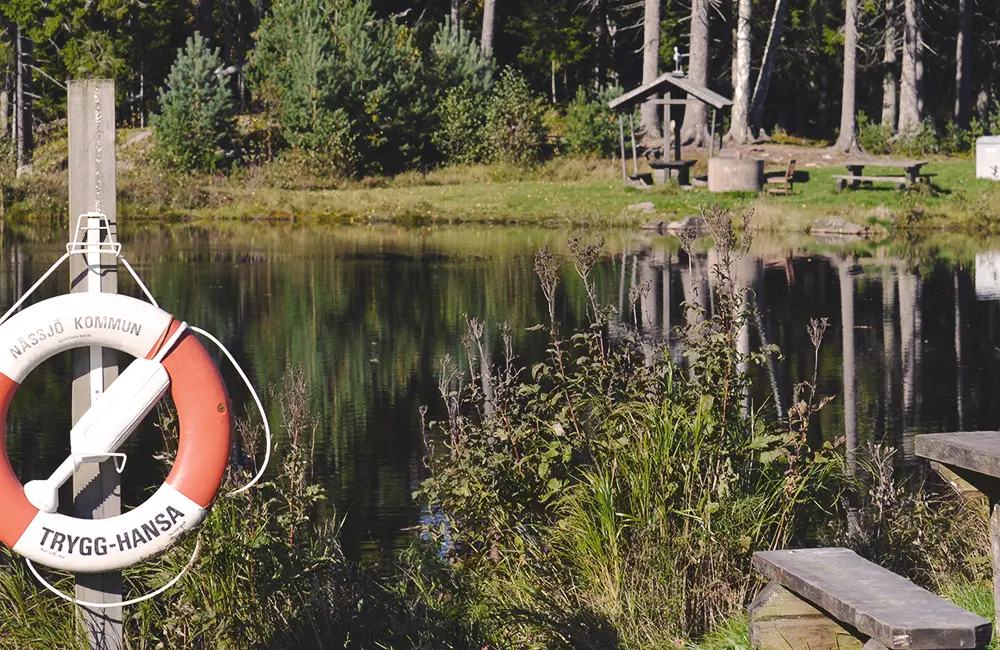 En spegelblank sjö, rastplats intill skogen.