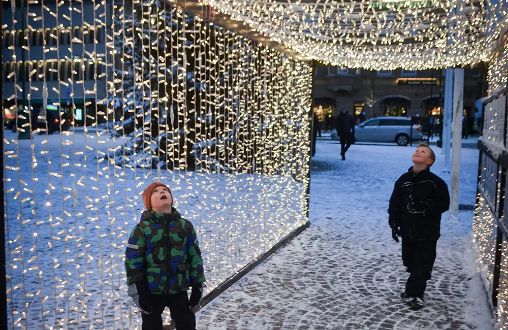 Två barn står i ljustunneln på stortorget i Nässjö och tittar förundransvärt upp på belysningen. 