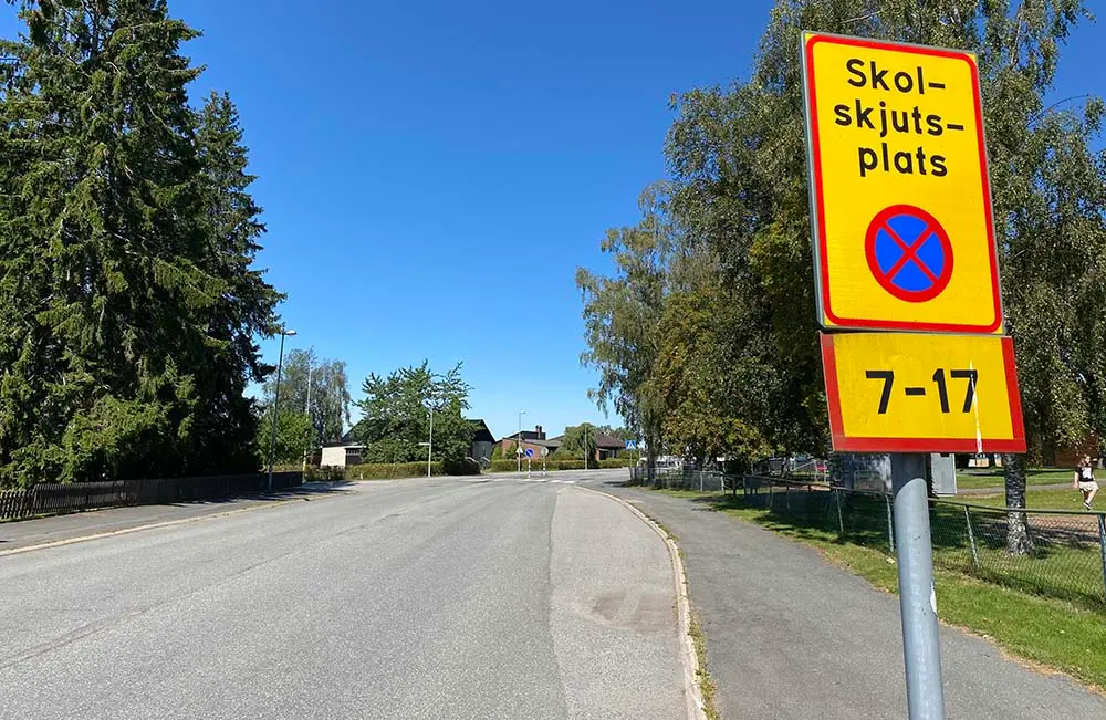 En vägskylt intill en busshållplats visar texten Skolskjutsplats, parkeringsförbud kl. 7-17.