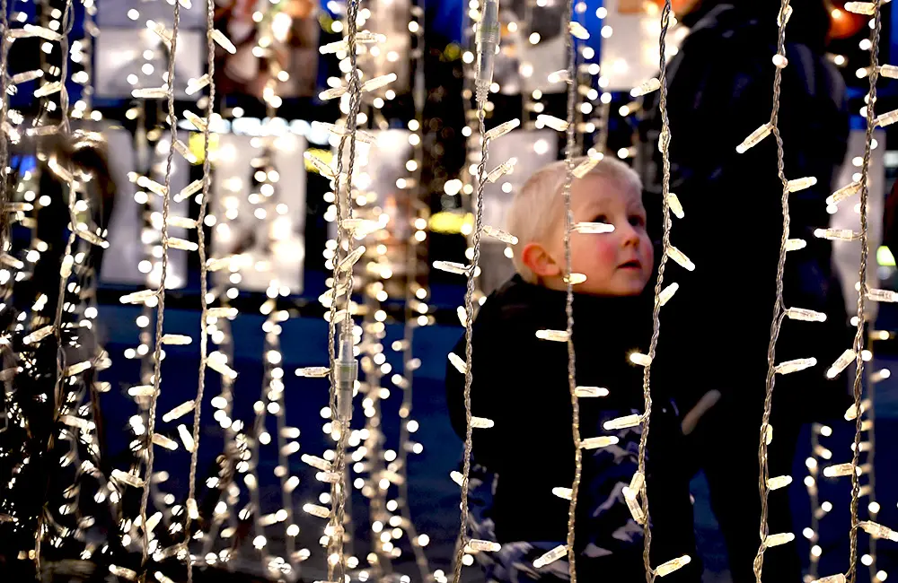 Liten pojke syns bakom en tunnel med ljusslingor.