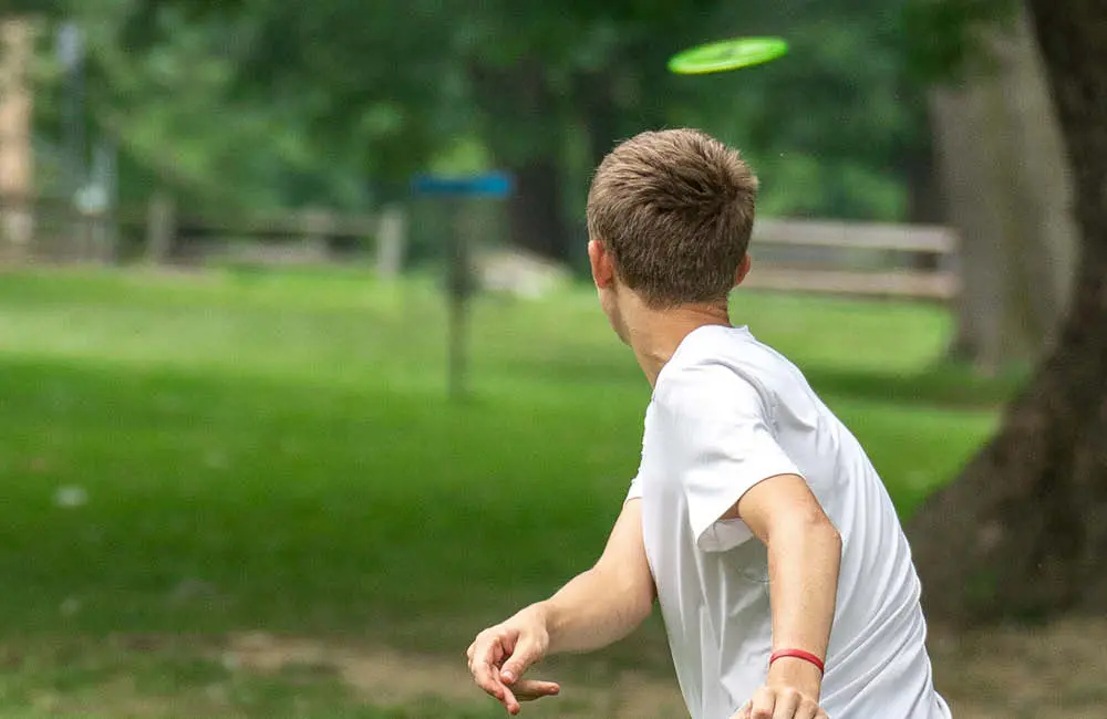 En person kastar frisbee i en park.