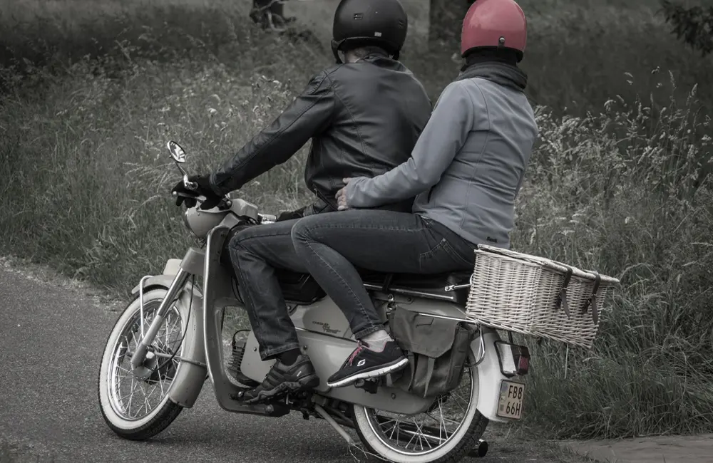 Två personer på en moped.