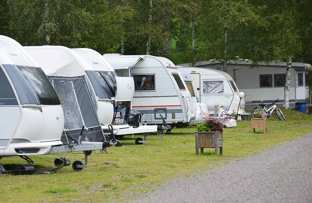 En rad husvagnsekipage längs en campinggata.