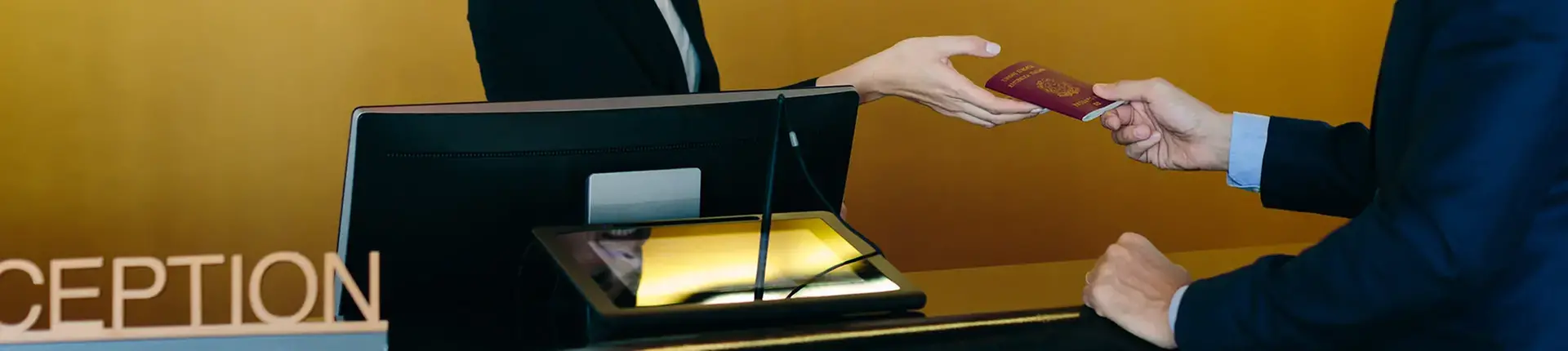 En person bakom en servicedisk räcker över ett rödbrunt pass till en annan person på kundsidan. På disken finns en datorskärm och en belyst glasskiva. Bakgrunden är enfärgad i gult.