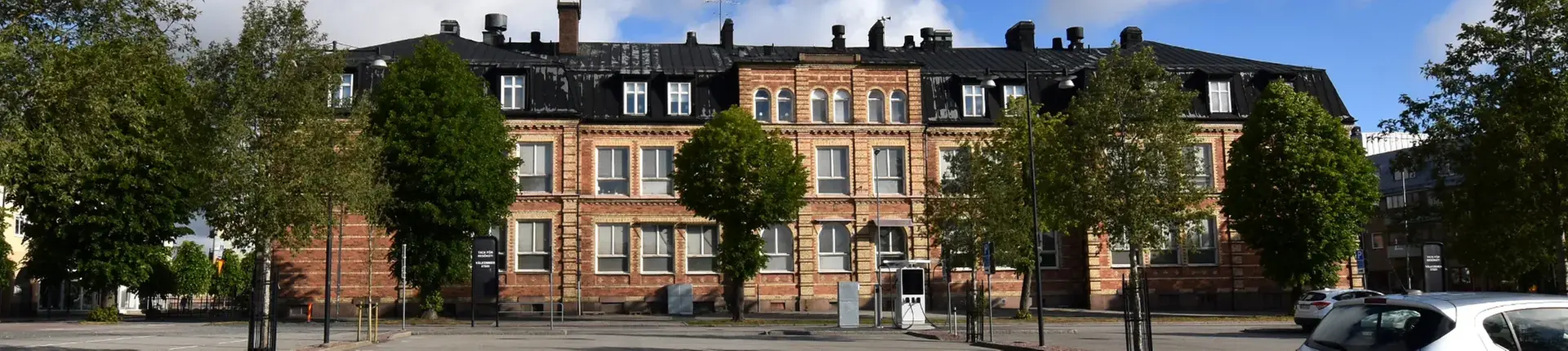 Nässjö lärcenters
  skolbyggnad i tegel bakifrån och omgivande grönskande träd.