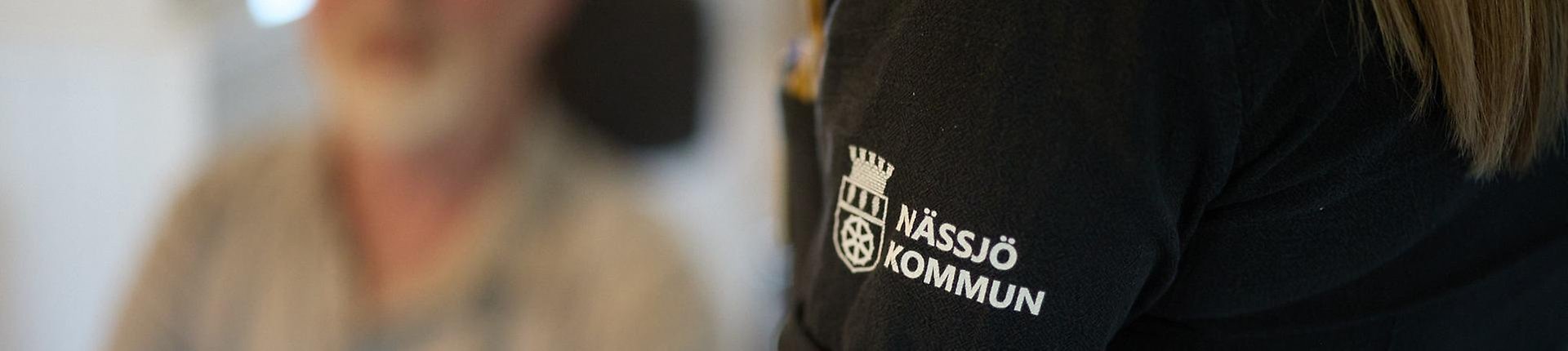 Tröja med Nässjö kommuns logotype samt en person i bakgrunden.
