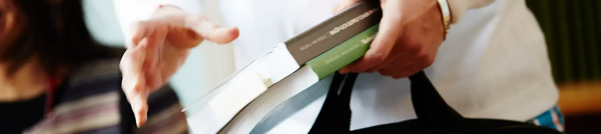 Händer som håller i studentlitteratur.