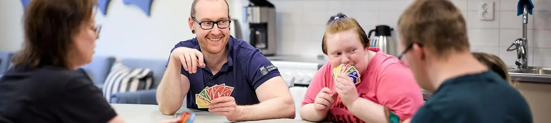 Människor som sitter runt ett bord och spelar kort.