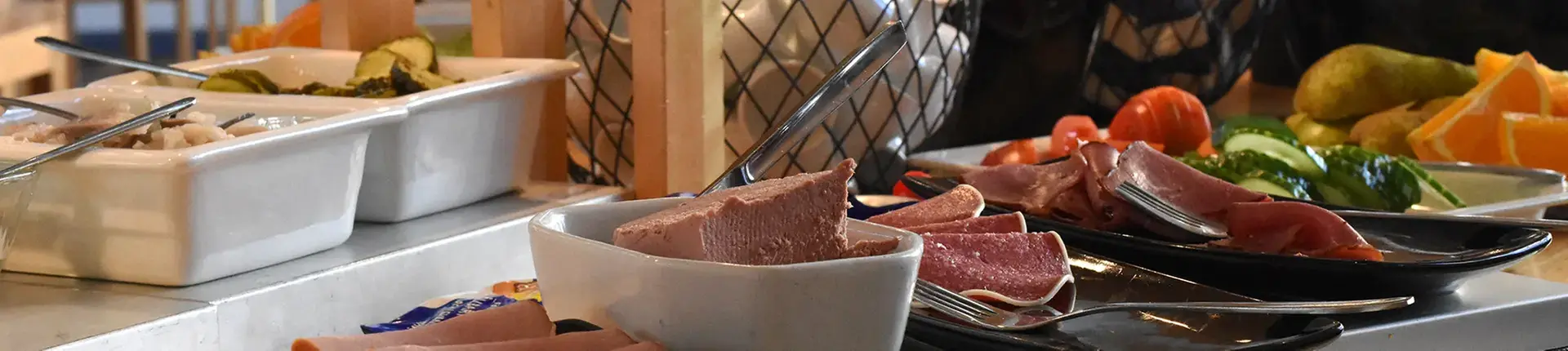 Uppdukat för frukost på restaurang med leverpastej, korv och grönsaker.