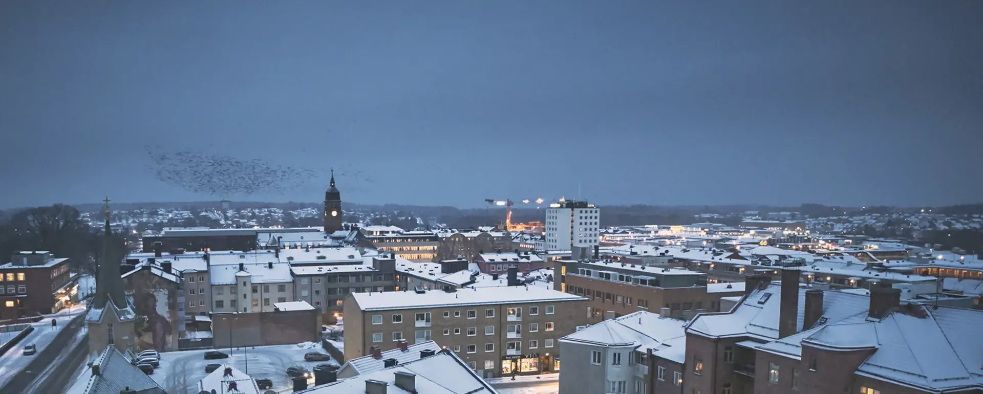 Vy över Nässjö stad på kvällen. Visar stadens byggnader där tak och gator är snöbelagda.