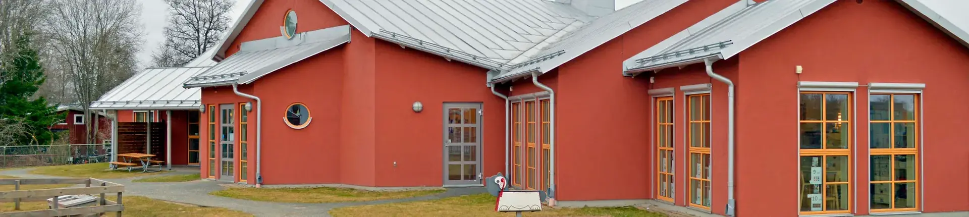 Byggnad med målad fasad i rött samt plåttak.