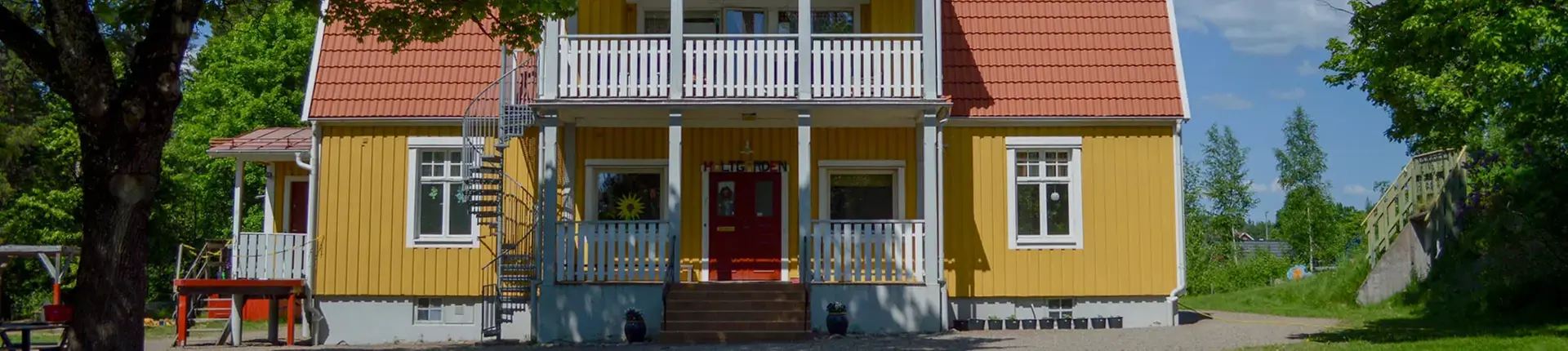 Gulmålad fasad på en byggnad med trädgård.