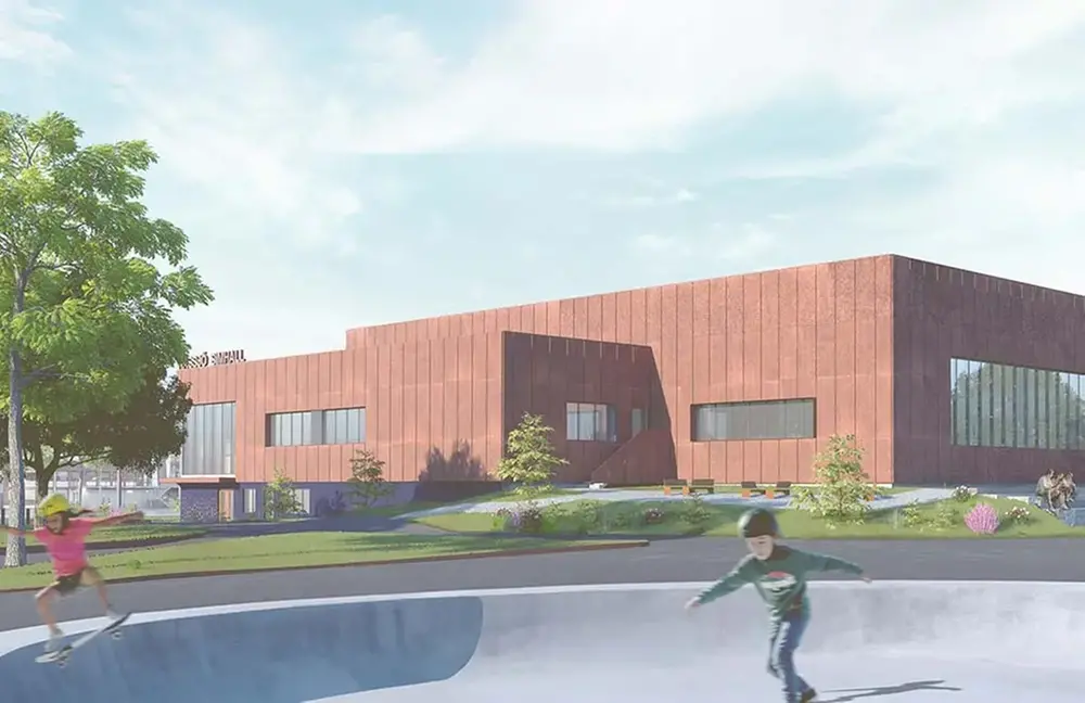 Två barn åker skateboard framför en modern byggnad i corténplåt.